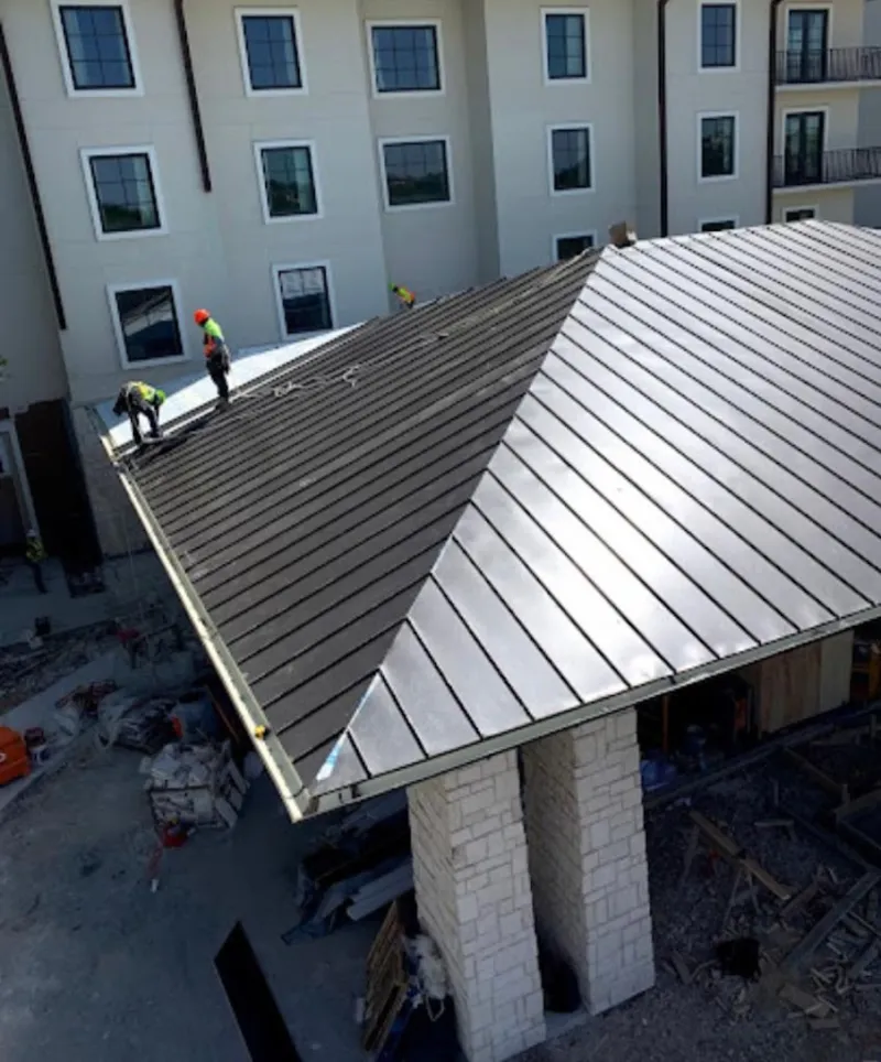 Crew installing standing seam metal roof panels on a commercial project in North Kansas City